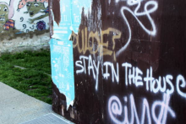image of graffiti on wall saying "stay in the house"
