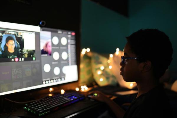 Silhouette of a student viewing a computer monitor in a darkened room. 