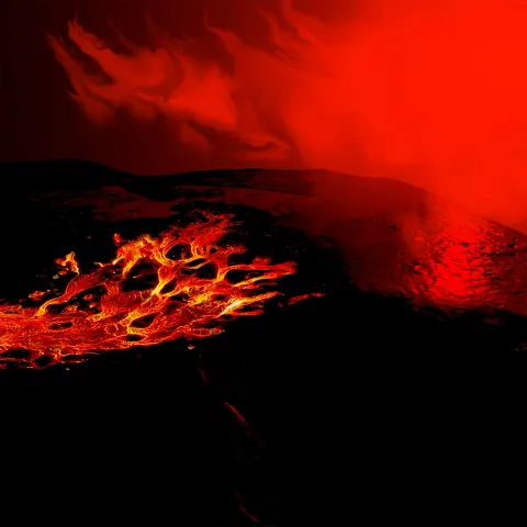 An overhead shot of a glowing, branched lava flow moving across a dark, volcanic landscape under a hazy, deep red sky.