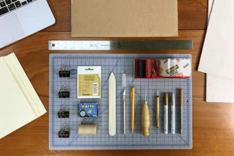 assorted maker's tools used for the abra codex including clips, xacto knife, tape, and pins