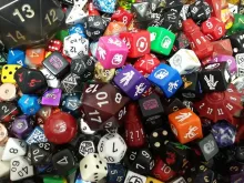 The image shows a colorful variety of dice used in tabletop gaming.