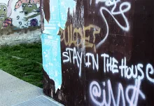 image of graffiti on wall saying "stay in the house"
