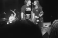 A smartphone takes a picture of two singers on stage.