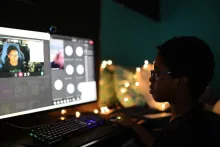 Silhouette of a student viewing a computer monitor in a darkened room. 