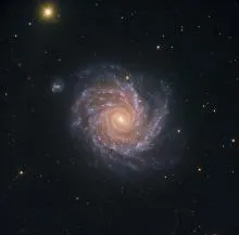 Spiral galaxy with bright central core and swirling arms, surrounded by scattered stars in deep space.
