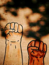 Graffiti of a black and white fist raised; the white fist is the higfher of the two.