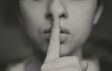 Close up of a person's mouth with one finger pressed against it, as if saying "shhh."