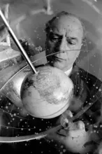 Marshall McLuhan looks at a spinning globe, black and white photo