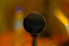Close-up of microphone with blurred colorful background, emphasizing mesh detail and shallow depth of field.